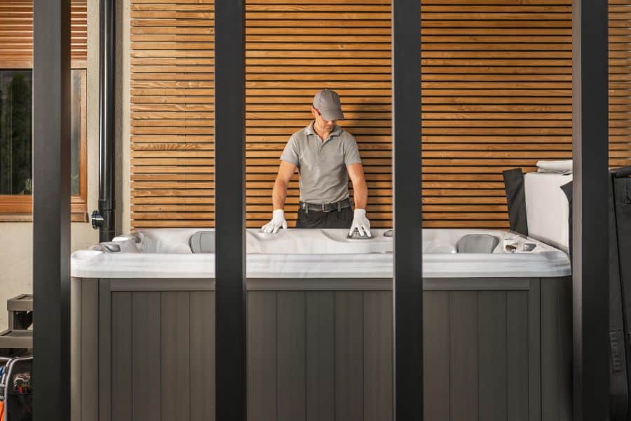 Worker in gloves and cap inspecting a spa before relocation process.